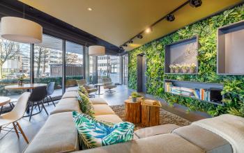 Modern office lobby at Hogehilweg 8, Amsterdam South East, featuring comfortable seating, greenery walls, and natural light. Ideal for businesses looking for office space rental in a stylish setting.