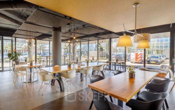 Modern office space rental at Hogehilweg 8, Amsterdam South East, featuring large windows, natural light, and contemporary seating arrangements for various working needs.