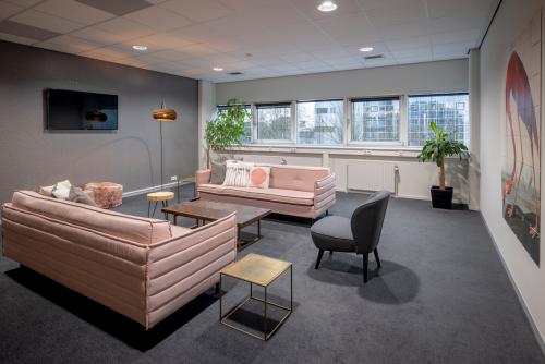 Comfortable lounge area with modern sofas and armchairs, large windows, and indoor plants at Hogehilweg 8, Amsterdam South East, Amsterdam. Ideal for office space rental.