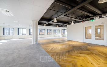 Modern office space available for rent at Karspeldreef 8, Amsterdam South East, featuring spacious interiors with a mix of carpet and wooden flooring.