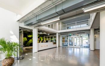 Spacious entrance area of an office to rent at Burgemeester Stramanweg 102, Amsterdam South East, featuring a modern reception desk and greenery for office space rental.