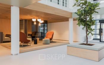 Spacious and modern office lounge in Amsterdam South East with stylish seating and natural lighting, ideal for office space rental.