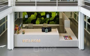 Modern reception area with a green wall and welcome sign at an office to rent in Amsterdam South East.