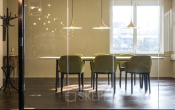 A stylish, glass-walled conference room at Burgemeester Stramanweg 102, Amsterdam South East, featuring a long table with modern chairs and pendant lighting, ideal for office space rental discussions.