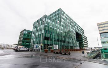 Exterior view of a modern glass building at Herikerbergweg 292, offering office space rental in Amsterdam South East.