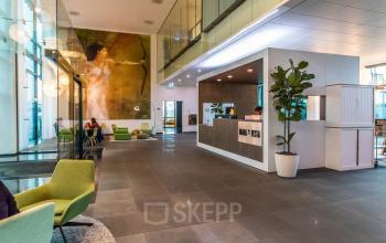 Modern office space with a reception desk and seating area at Herikerbergweg 292, ideal for office space rental in Amsterdam South East.