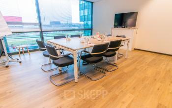 Spacious office to rent at Herikerbergweg 292, Amsterdam South East, featuring a meeting room with a large table, chairs, and a TV, ideal for office space rental.