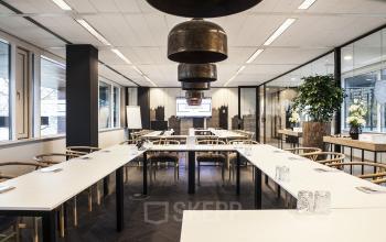Modern conference room with large windows, arranged with white tables in U-shape, and wooden chairs, at De Entree 99-197 in Amsterdam South East, Amsterdam.