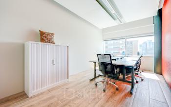 Bright office space rental in Amsterdam South East with modern furniture, a large window, and natural light.