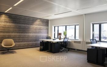 Modern office to rent at De Entree 99-197, Amsterdam South East, featuring spacious workstations, large windows, and a cozy chair.