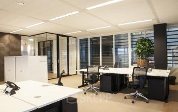Modern office space rental at De Entree 99-197, Amsterdam South East, featuring open workspaces with desks, chairs, and cabinets.