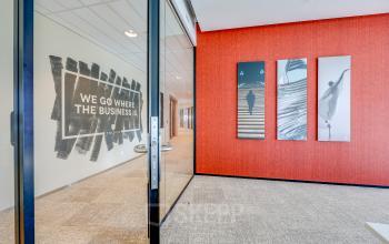Bright office space in Amsterdam South East with modern decor, featuring wall art and a glass partition.