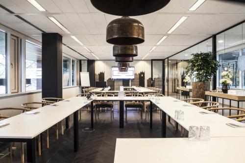 Modern conference room with large windows, arranged with white tables in U-shape, and wooden chairs, at De Entree 99-197 in Amsterdam South East, Amsterdam.