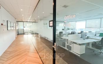 Modern office space featuring glass walls, desks, and chairs, located at De Entree 230, Amsterdam South East, available for office space rental.