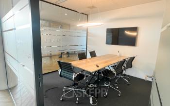 Modern conference room at De Entree 230, Amsterdam South East featuring a sleek wooden table and black chairs, ideal for office space rental.