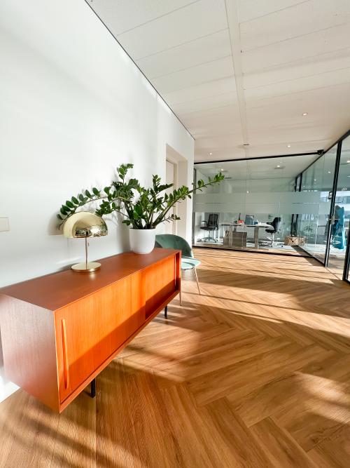 Modern office space rental at De Entree 230, Amsterdam South East, with warm wooden flooring, contemporary furnishings and ample natural light.