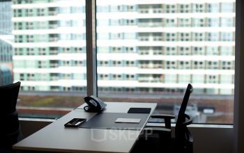 Modern office space rental at Parnassusweg 819, Amsterdam Zuidas with a well-equipped desk and a city view.