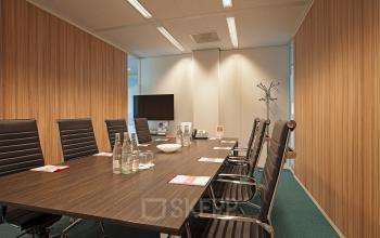Elegantly appointed conference room available for office space rental at Parnassusweg 819, Amsterdam Zuidas, with a large table, chairs, and a flat-screen TV.