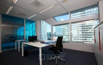 Modern office space rental at Parnassusweg 819, Amsterdam Zuidas, with a sleek desk, ergonomic chairs, and expansive windows overlooking the city.