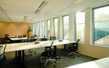 Bright office space with large windows, modern desks, and office chairs at Jachthavenweg 109-A, Amsterdam Zuidas. Ideal for office space rental.