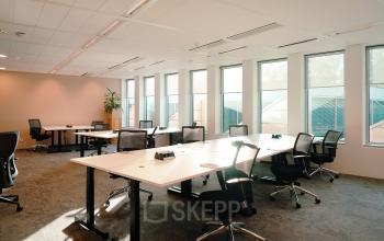 Spacious and well-lit office to rent at Jachthavenweg 109-A, Amsterdam Zuidas featuring multiple desks, ergonomic chairs, and large windows providing natural light.
