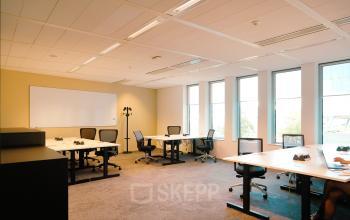 Bright office space with several desks and chairs, whiteboard on the wall, and large windows at Jachthavenweg 109-A, Amsterdam Zuidas.