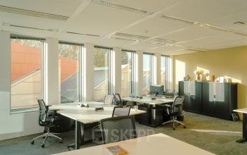 Bright office space rental at Jachthavenweg 109-A, Amsterdam Zuidas, featuring multiple workstations, ergonomic chairs, large windows, and storage cabinets.