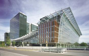 Modern office space rental at Zuidplein 36, Amsterdam Zuidas with a striking glass facade and lush greenery.