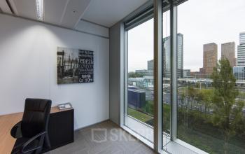 Office space rental at Zuidplein 36, Amsterdam Zuidas, with a view of the cityscape through large windows and a well-appointed interior.