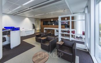 Modern office space rental at Zuidplein 36, Amsterdam Zuidas, showcasing a stylish lounge area with comfortable seating and a welcoming atmosphere.