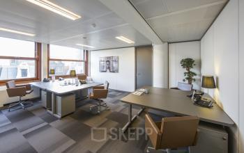 Modern office space rental at Zuidplein 36, Amsterdam Zuidas with large windows, desks, chairs, and office equipment.
