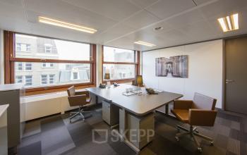 Modern furnished office space rental at Zuidplein 36, Amsterdam Zuidas, with large windows, sleek desks, and office chairs.
