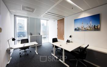 Modern office space rental at Zuidplein 36, Amsterdam Zuidas, with ergonomic chairs and a vibrant cityscape picture on the wall.
