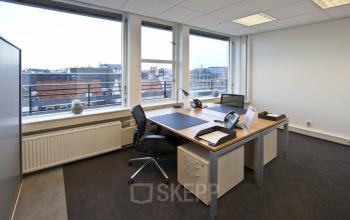 Modern furnished office at Zuidplein 36, Amsterdam Zuidas, with a spacious desk, chairs, and a bright window view, ideal for office space rental.