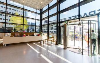 Bright entrance area of an office space at Barbara Strozzilaan 101-201, Amsterdam Zuidas, with large windows and people entering. Ideal for office space rental.