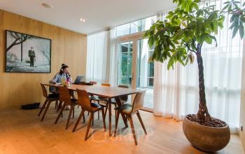 Modern office space in Amsterdam Zuidas at Barbara Strozzilaan 101-201 featuring a wooden table with individuals engaged in business activities, large windows, and greenery, ideal for office space rental.