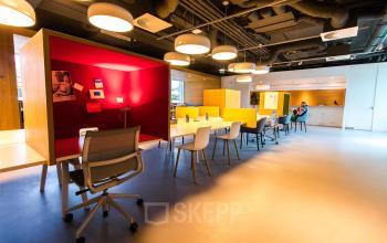 Bright office space with modern furnishings at Barbara Strozzilaan 101-201, Amsterdam Zuidas. People are working at shared desks. Ideal for office space rental.