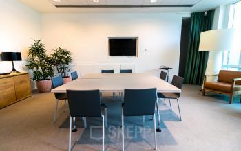 Office space for rent at Barbara Strozzilaan 101-201, Amsterdam Zuidas, featuring a modern conference room with a table, chairs, and minimal decor.