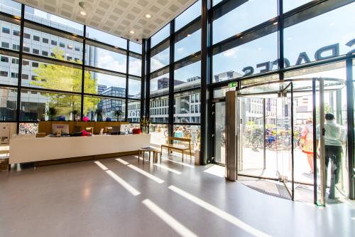 Bright entrance area of an office space at Barbara Strozzilaan 101-201, Amsterdam Zuidas, with large windows and people entering. Ideal for office space rental.