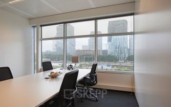 Spacious and well-lit office space rental at Strawinskylaan 3051 in Amsterdam Zuidas, featuring a modern meeting room with a city view.