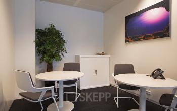 Modern office space rental at Strawinskylaan 3051, Amsterdam Zuidas, featuring a round table with comfortable chairs for small meetings.