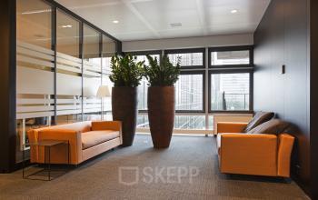 Elegant lounge area at Strawinskylaan 3051 office space rental, furnished with comfortable seating and lush plants, in Amsterdam Zuidas.