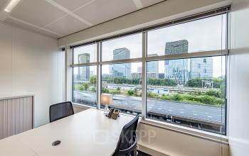 Modern office space rental at Strawinskylaan 3051, Amsterdam Zuidas, with a bright workspace, city views, and neatly organized desks.