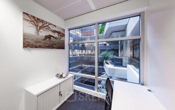 Office space rental at Strawinskylaan 3051, Amsterdam Zuidas, showcasing a well-lit corner office with large windows and modern furnishings.