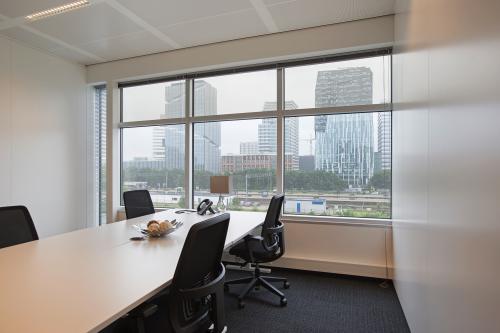 Spacious and well-lit office space rental at Strawinskylaan 3051 in Amsterdam Zuidas, featuring a modern meeting room with a city view.