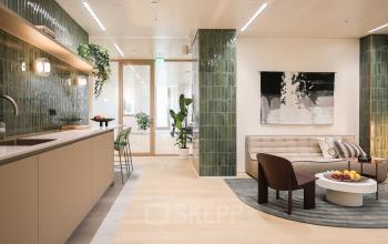 Stylish office lounge in Amsterdam Zuidas at Beethovenstraat 503, featuring modern furniture and a kitchenette, perfect for office space rental. Ideal setting for informal meetings or relaxing breaks.