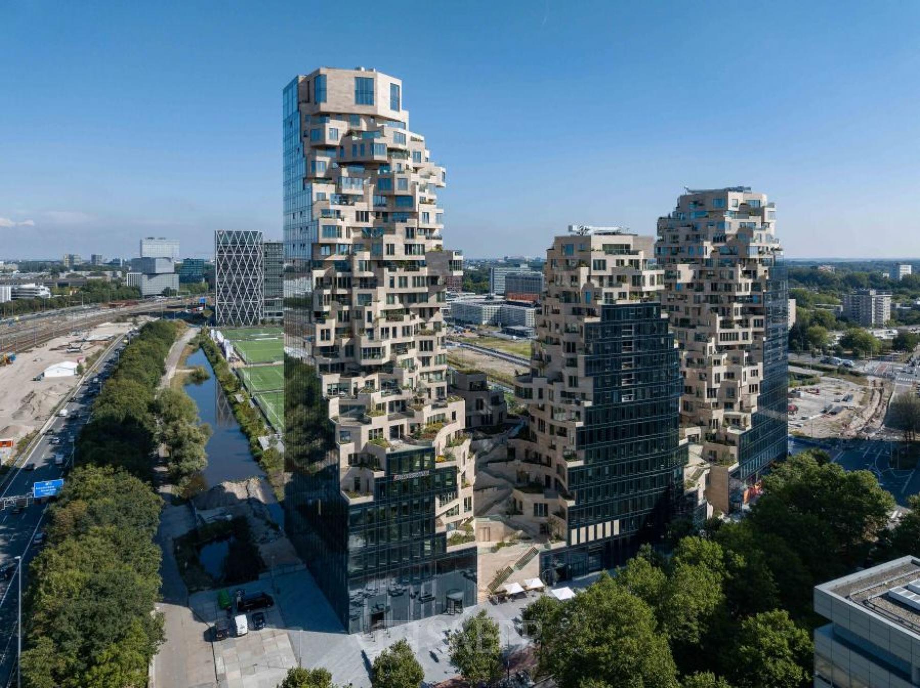 A modern architectural exterior of Beethovenstraat 503 in Amsterdam Zuidas, showcasing unique, contoured facades amidst urban surroundings. Ideal location for office space rental with panoramic views and proximity to key business hubs.