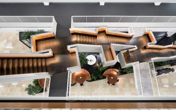 Modern office space at Fred. Roeskestraat 115 in Amsterdam Zuidas featuring unique, geometric staircase design with surrounding plants and seating areas, ideal for open floor plan office space rental.