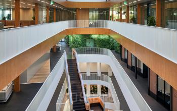 Bright, modern office interior at Fred. Roeskestraat 115 in Amsterdam Zuidas, featuring a multi-level atrium with large skylights, plants, and staircases. Ideal for office space rental.