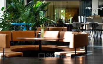 Modern lounge area at Fred. Roeskestraat 115, Amsterdam Zuidas, featuring stylish circular seating and abundant natural light. Ideal for office space rental with versatile environments for meetings and casual workspaces.
